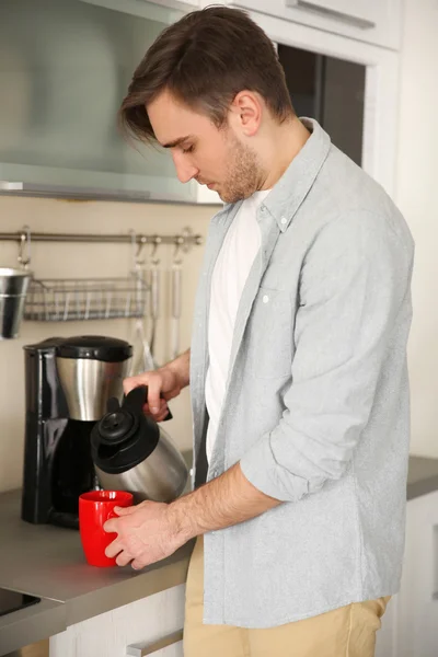 Young man pouring coffee into cup — Stock Photo, Image