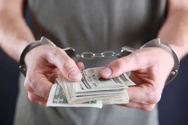 Man in handcuffs counting dollar banknotes — Stock Photo, Image