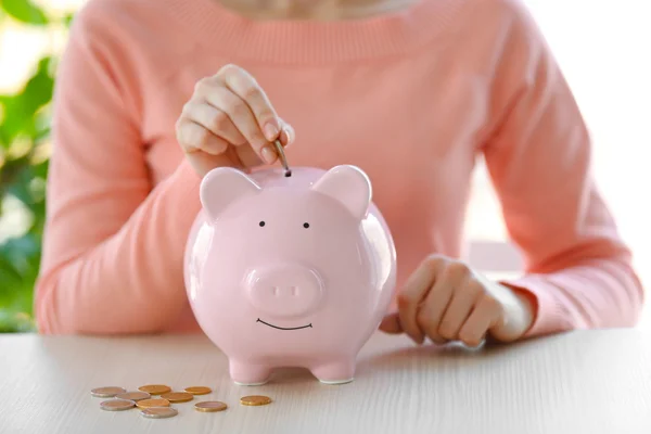 Woman putting money in piggy bank — Stock Photo, Image