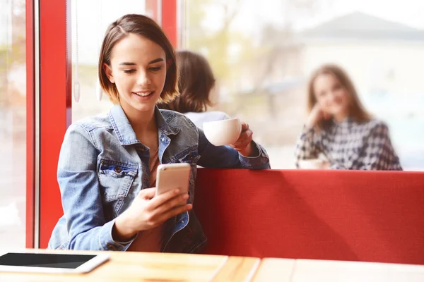 Жінка сидить у кафе зі смартфоном — стокове фото