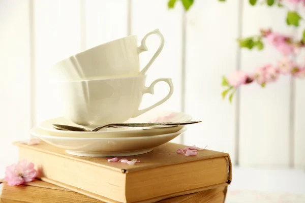 Porseleinen kopjes met boeken en bloemen — Stockfoto