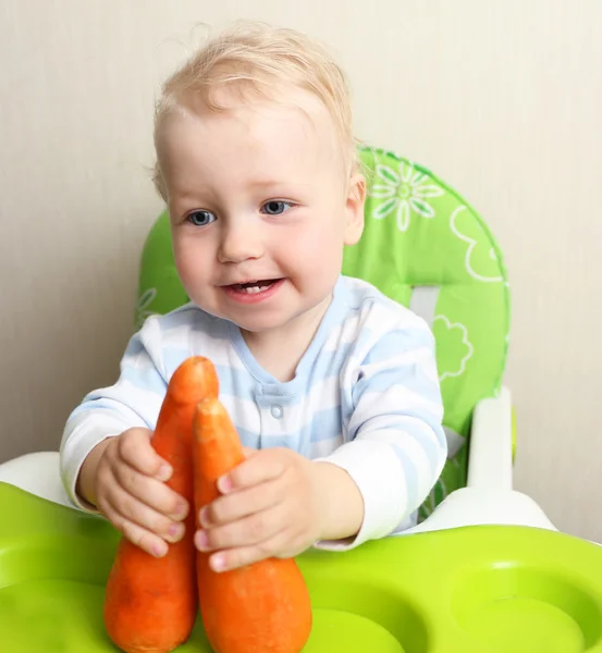 Cute baby playing with carrots — Stock Photo, Image