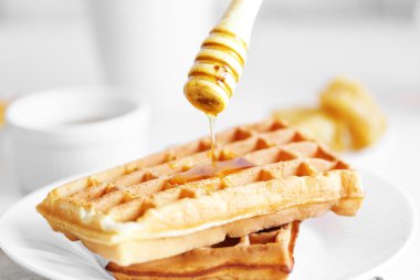 Pouring honey on waffles clipart