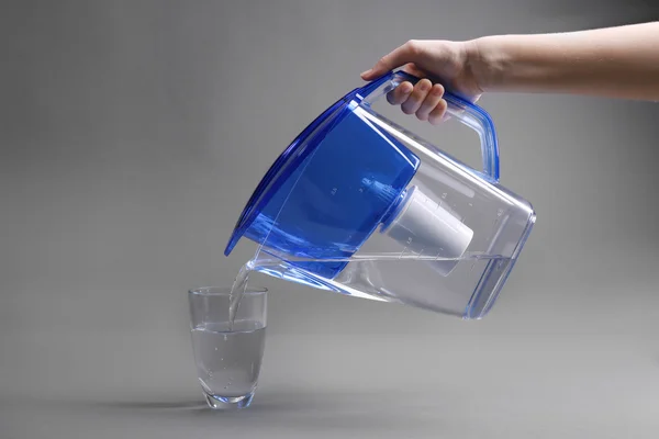 Hand gießt gefiltertes Wasser in Glas — Stockfoto