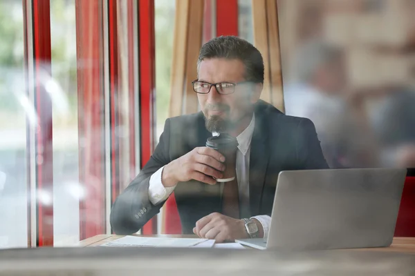 Уверенный бизнесмен с кофе и ноутбуком — стоковое фото