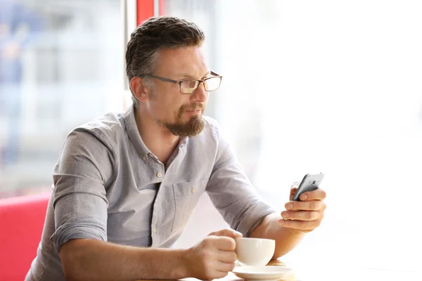 Бизнесмен с сотовым телефоном и чашкой кофе — стоковое фото