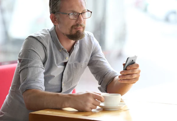 Бизнесмен с сотовым телефоном и чашкой кофе — стоковое фото