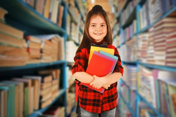 Flicka med böcker i biblioteket — Stockfoto