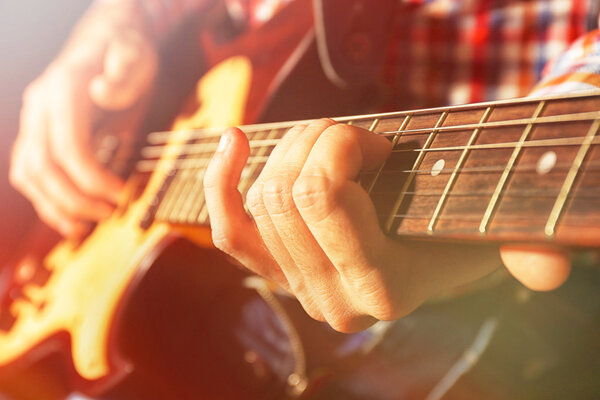 Young man playing on electric guitar 