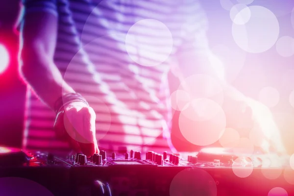 DJ играет музыку на миксере на разноцветном размытом фоне — стоковое фото