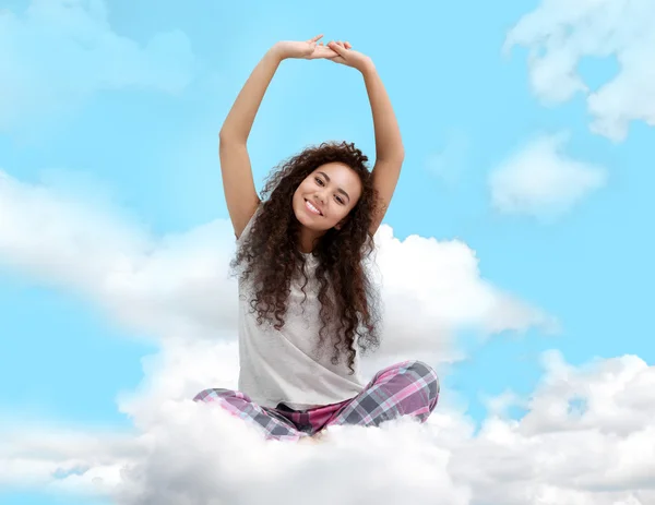 Woman in pajamas sitting on cloudy sky — Stock Photo, Image