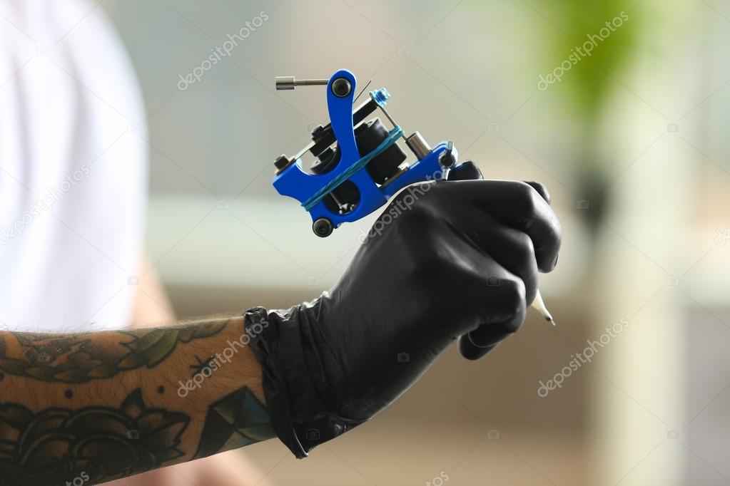 Man's hand holding tattoo machine Stock Photo by ©belchonock 113529524