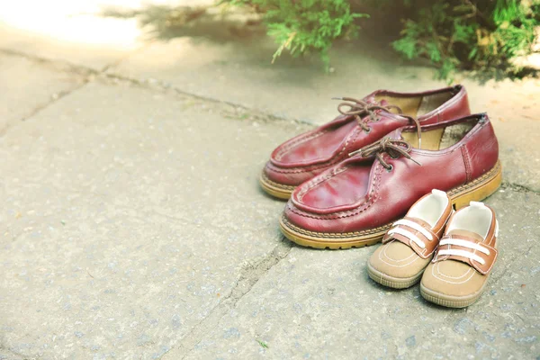 Vader schoenen dicht bij kind schoenen — Stockfoto