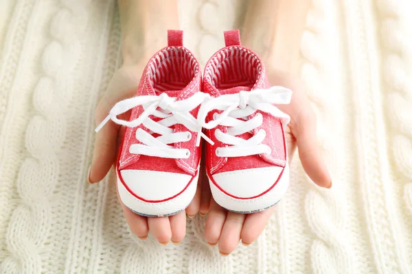 Woman holding baby sport boots — Stock Photo, Image