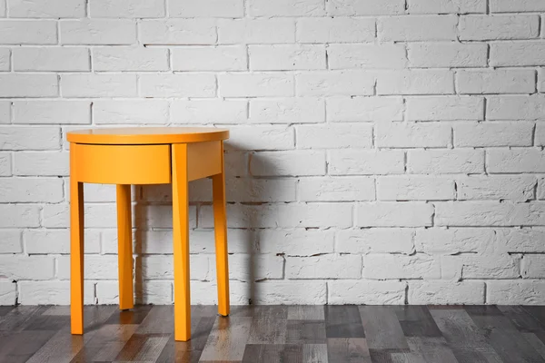 Желтый стол у кирпичной стены — стоковое фото