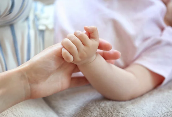 Kvinna anläggning liten bebis hand — Stockfoto