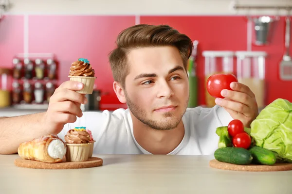 Homem com alimentos saudáveis e não saudáveis — Fotografia de Stock