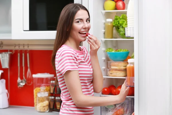Junge Frau steht neben Kühlschrank — Stockfoto