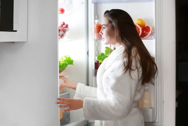 Vrouw op zoek naar de koelkast bij nacht — Stockfoto