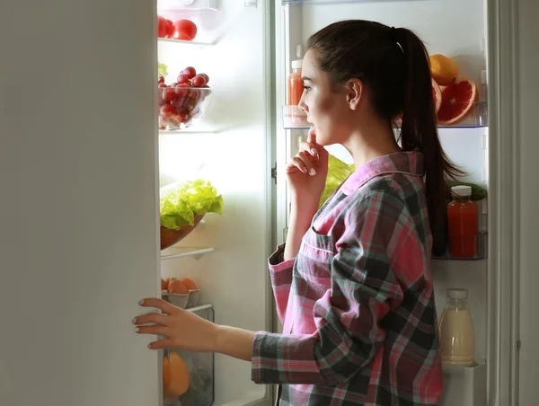 Frau schaut nachts in Kühlschrank — Stockfoto