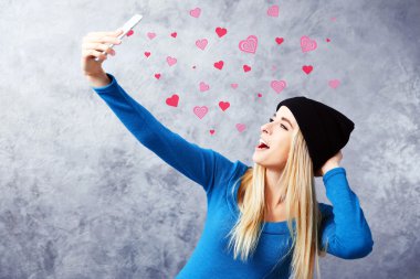 Siyah şapkalı akıllı telefon gri duvar arka planda tutan genç kız