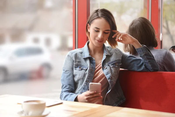 Жінка сидить у кафе зі смартфоном — стокове фото