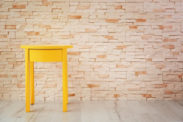 Mesa amarilla en la pared de ladrillo —  Fotos de Stock