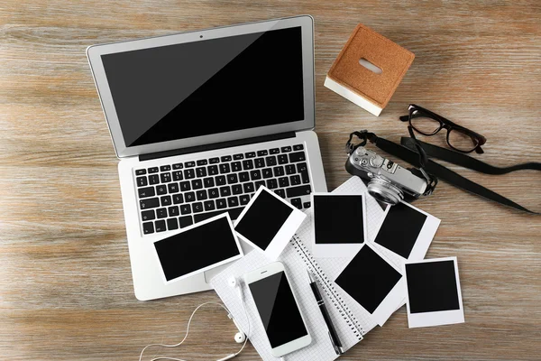 Laptop, telefone, fotos em uma mesa de madeira — Fotografia de Stock