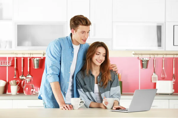 Pareja con portátil en la cocina — Foto de Stock