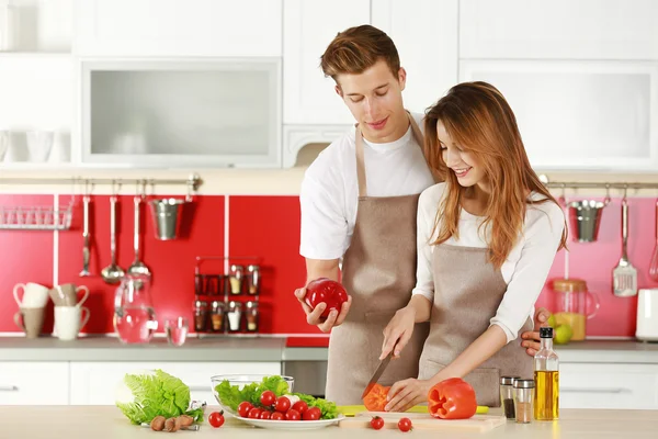 Par i forklæder madlavning i køkkenet - Stock-foto