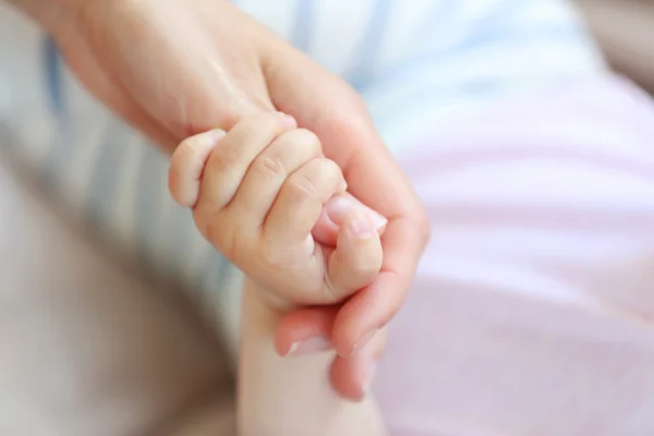 Frau hält kleine Babyhand — Stockfoto