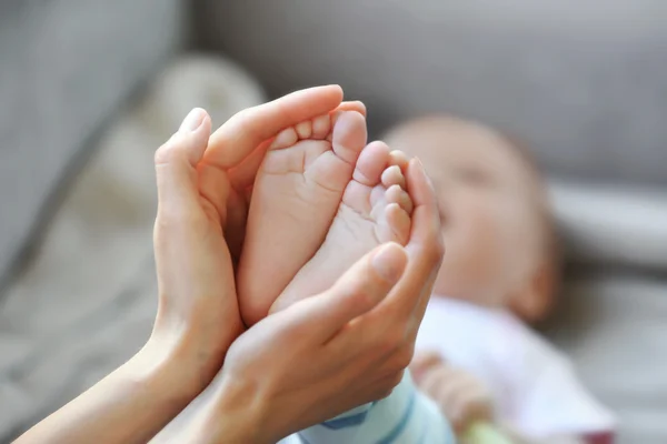 Donna che tiene piccoli piedi del bambino — Foto Stock