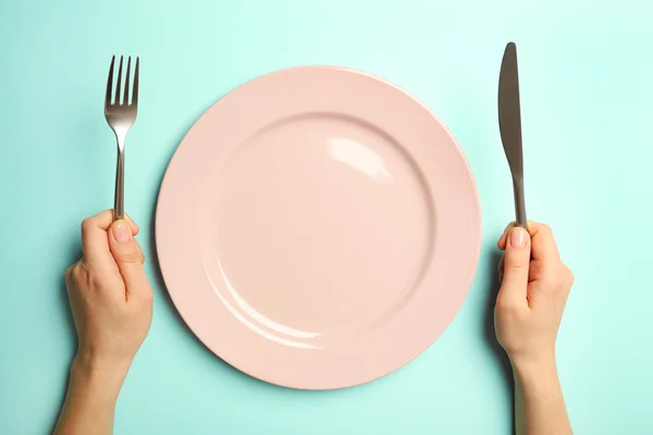 Mains féminines avec couverts et assiette vide — Photo