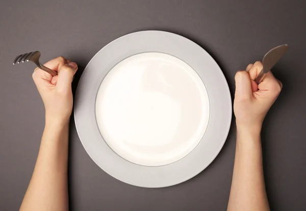 Женские руки со столовыми приборами и пустой тарелкой — стоковое фото