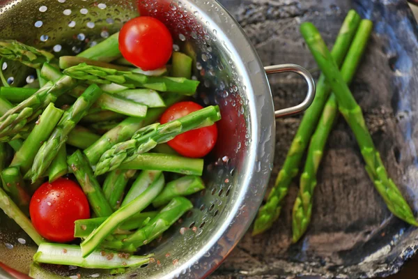 Espargos com tomates em escorredor — Fotografia de Stock