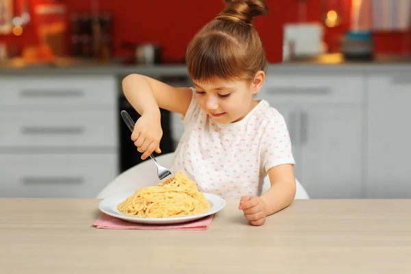 Adorable little girl eating spaghetti