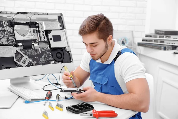 Young repairer working with soldering iron in service center — Stock Photo, Image