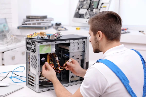 Joven reparador desarmando una computadora partes internas en el centro de servicio —  Fotos de Stock