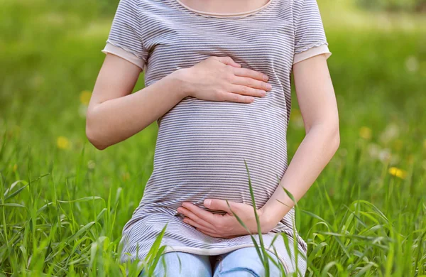 Femme enceinte assise sur l'herbe — Photo