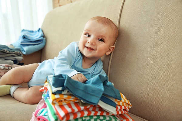 Adorable bébé avec des piles de vêtements — Photo