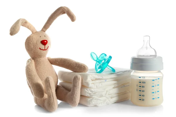 Baby bottle with milk, pile of diapers — Stock Photo, Image