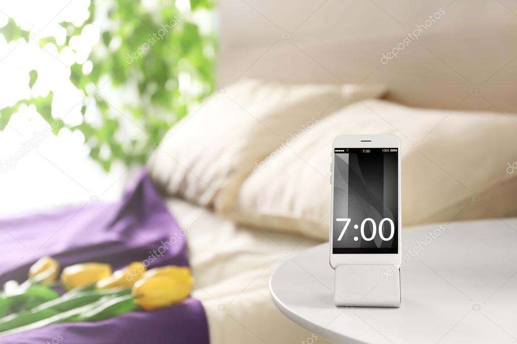 Smart phone with stand on a bedside table in a room