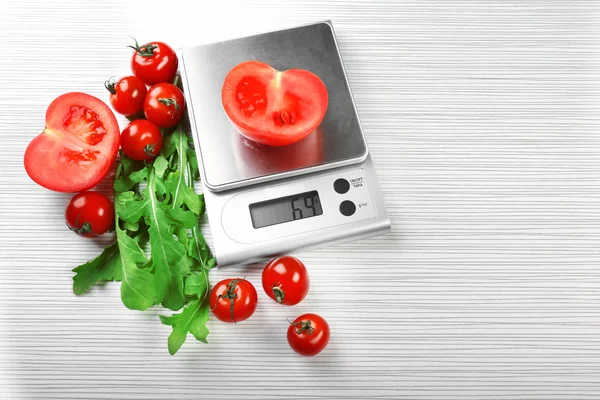 Помидоры с цифровыми весами на кухне — стоковое фото