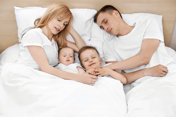 Onnellinen perhe valkoisella sängyllä — kuvapankkivalokuva