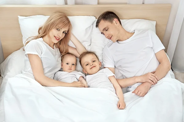 Happy family on white bed — Stock Photo, Image