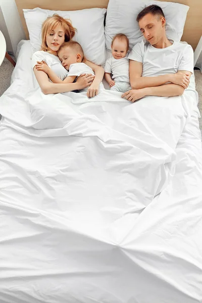 Lycklig familj på vit säng — Stockfoto
