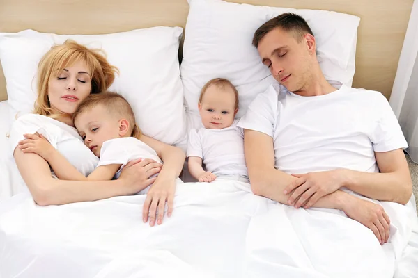 Onnellinen perhe valkoisella sängyllä — kuvapankkivalokuva