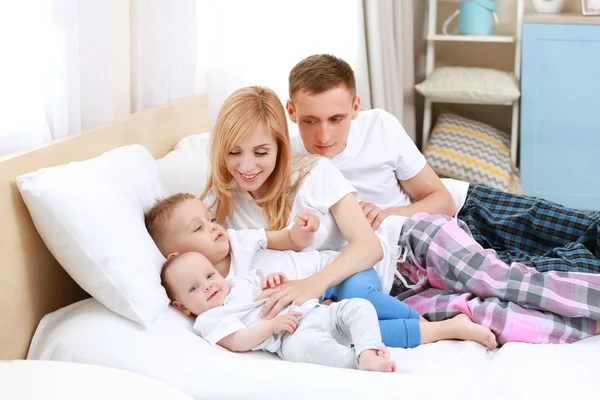 Gelukkige familie op witte bed — Stockfoto