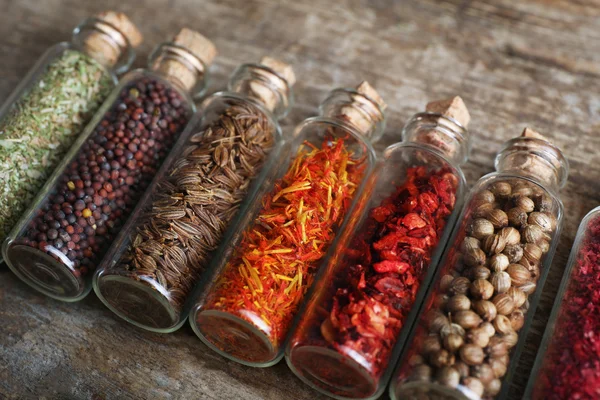 Especiarias diferentes em pequenas garrafas de vidro — Fotografia de Stock