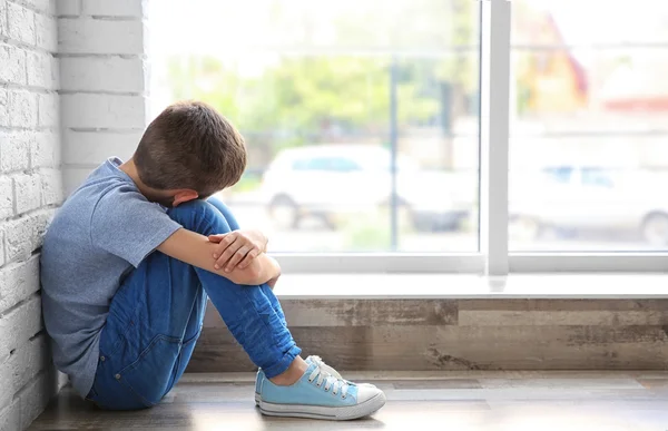 Niño triste sentado cerca de la ventana — Foto de Stock